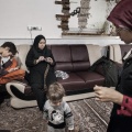Reyhane, 21, is a shiite muslim woman, in her living room with her mother Zohre, doing the crochet, and the two brothers Ali and Mahdi. Nooshabad, Iran. December 2014.